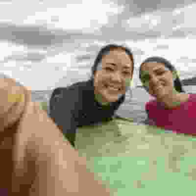 Two women taking selfie on a surfboard in Playa Carrillo. 