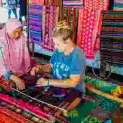 Women traveller taking part in sewing lesson with a local in Sasak Village.