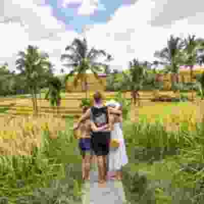 Three travellers with their arms round each other in rice fields in Jatiluwih.