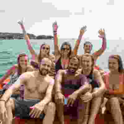 Group of travellers with their hands in the air on a boat trip in Koh Rong.
