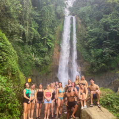 Group of travellers smiling under a waterfall in Lovina.