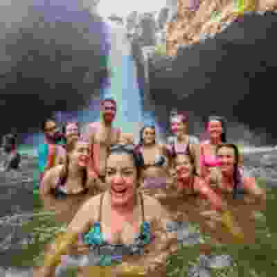 Group of travellers laughing in the water at the bottom of the Tegenungan waterfall.