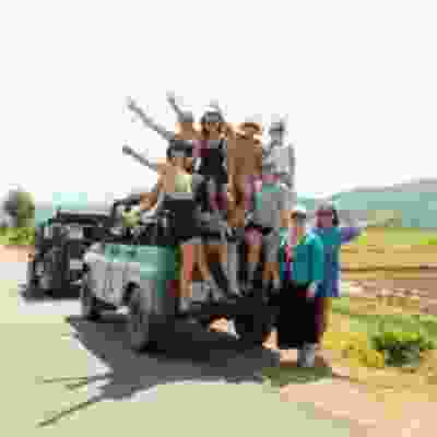 Group of travellers smiling on the back of a jeep.