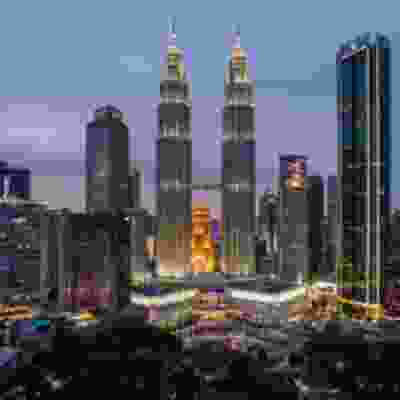Landscape view of lit up Kuala Lumpur skyline at night time.