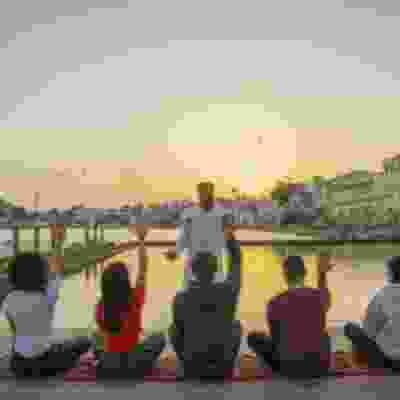Group of travellers meditating at sunset in front of Pushkar Lake.