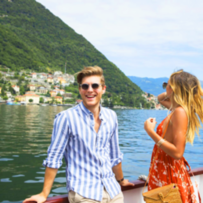 A couple stood up leaning against side of boat whilst travelling down lake Como.