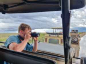 Traveller in a safari jeep taking photos of wildlife with a camera
