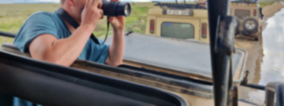 Traveller in a safari jeep taking photos of wildlife with a camera